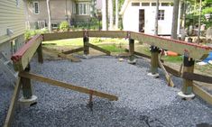 a wooden bench sitting in the middle of a gravel covered yard next to a house