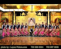 a group of people posing for a photo in front of a stage with a bride and groom