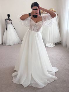 a woman taking a selfie while wearing a wedding dress in front of mannequins