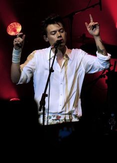 a man standing in front of a microphone and holding up two fingers to the air