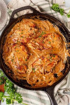 a skillet filled with meat and sauce on top of a table