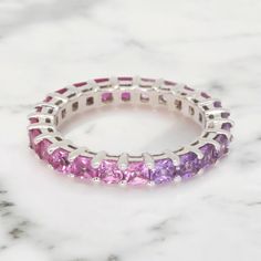 This unique Natural Pink Sapphire Ring is sure to garner you compliments. With its seamless pink to purple gradient and fine gold finishing, it's a purchase you can be proud of. ◆ Metals Details ◆ Metal: 14K & 18K Solid Gold Colors: White, Yellow & Rose Gold ◆ Stone Details ◆ Stone: Natural Sapphires Stone Size: 2.8mm Stone Shape: Princess Cut (Square) Stone Color: Pink to Purple  ◆ Shipping Details ◆ Shipping: Via FedEx Express Processing Time: 5 to 10 Days Delivery: 5 to 7 Days Tracking ID provided ◆ Customization ◆ If you want to modify the ring, whether it be stone size, metal engraving, custom design or any other requests, please feel free to message us! We undertake all sorts of personalisation requests and custom jewelry orders. :) ◆ Returns ◆ Each piece of jewelry is custom made to Fine Jewelry Pink Sapphire Ring In Purple, Luxury Pink Stackable Jewelry, Pink Eternity Band Fine Jewelry, Pink Gemstone Eternity Band Fine Jewelry, Fine Jewelry Pink Eternity Band With Gemstone, Luxury Pink Amethyst Ring With Prong Setting, Luxury Pink Half Eternity Rings, Pink Multi-stone Amethyst Ring Gift, Luxury Pink Amethyst Jewelry