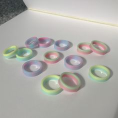 several different colored rings sitting on top of a white table next to a black object