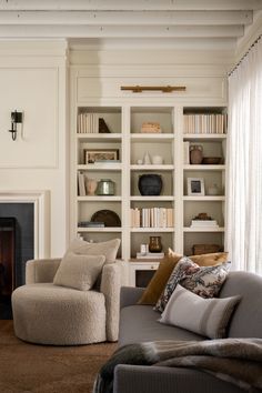 a living room filled with lots of furniture and bookshelves next to a fire place