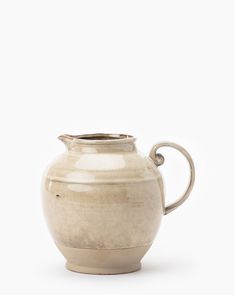 a cream colored ceramic pitcher with handle on a white background for use as a vase