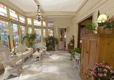 the sun shines through large windows in an ornately decorated room with white furniture and potted plants