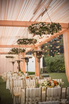 an outdoor wedding venue set up with white linens and floral arrangements hanging from the ceiling