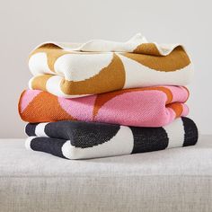 four folded towels stacked on top of each other in different colors and patterns, with one folded up to the side