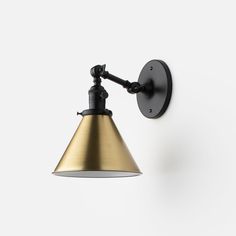 an industrial style wall light in black and gold with a white back droplet shade