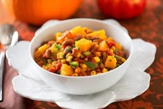 a white bowl filled with food on top of a table next to an orange pumpkin