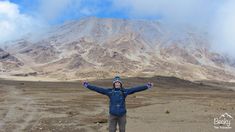 a person standing in front of a mountain with their arms spread out and hands outstretched