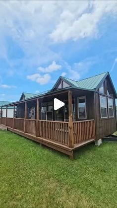 a mobile home sits in the middle of a grassy field with blue sky and clouds