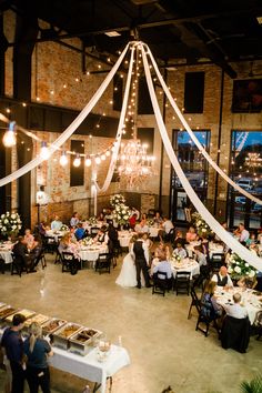 an indoor wedding reception with white draping and chandeliers