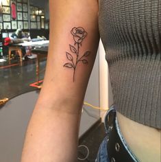 a woman's arm with a rose tattoo on the left side of her arm