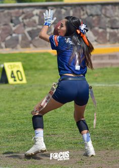 a female lacrosse player in action on the field with her hands up and one hand raised