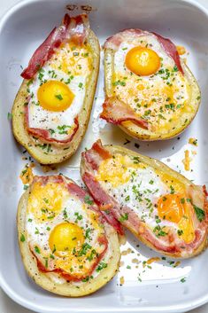 four eggs and bacon on top of potato skins in a white baking dish with parmesan sprinkles