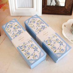 two blue boxes sitting on top of a counter next to a plate with a cupcake