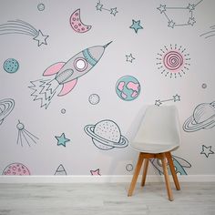 a white chair sitting in front of a wall with colorful space related drawings on it