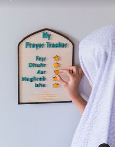 a person is writing on a plaque with stars in it that says, my prayer tracker