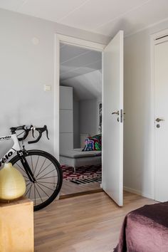 there is a bike that is parked in the room next to the bed and door