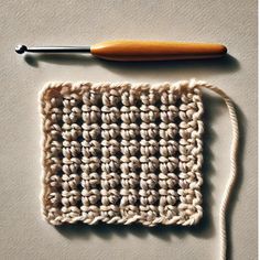 the crochet square is next to a knitting needle