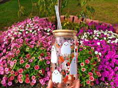 a person holding up a glass with some stickers on it in front of flowers