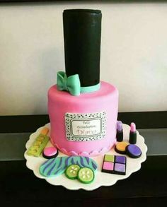 a pink cake decorated with buttons and sewing accessories on a plate next to a wall