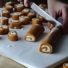 a person is cutting up some food on a white board with orange and white icing