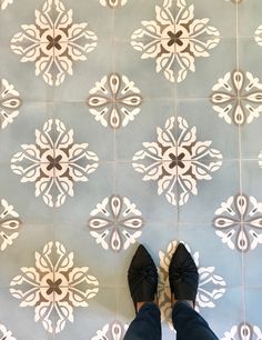 a person standing on a tile floor with their feet up in front of the tiles