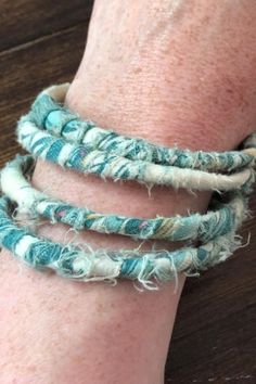 a close up of a person's arm wearing three bracelets with torn fabric