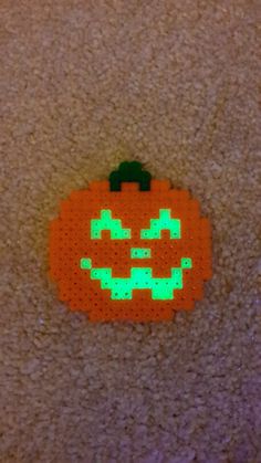 an orange pumpkin with green eyes is on the floor in front of a carpeted area