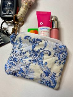 a blue and white purse with various items on it next to a keychain