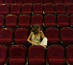 a woman is sitting in the middle of an empty auditorium