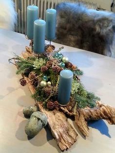 a wooden log with candles on top of it and pine cones in the middle, along with other decorations