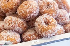 a pile of sugar covered donuts sitting on top of a white tray