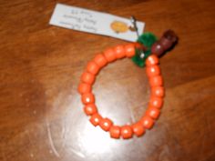 an orange beaded bracelet with a small brown dog on it's end and a name tag