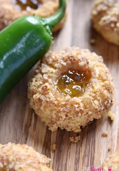 some food is laying on a wooden table with a green pepper in the middle and two pieces of bread next to it