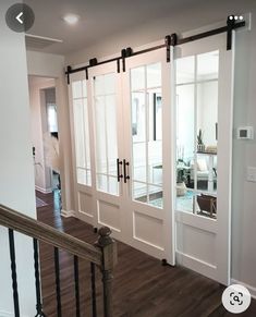 an open door leading to a living room with hardwood floors and white walls in the background