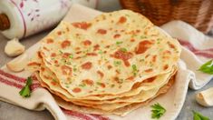 three flat breads on a plate with garlic and parsley in the background, ready to be eaten