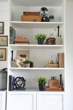 a white book shelf filled with lots of books and potted plants on top of it