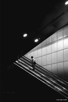 a man walking down an escalator next to a wall with tiles on it