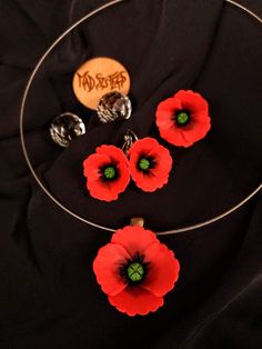 Discover the timeless beauty of our handcrafted jewelry set, where each piece has been meticulously shaped from high-quality polymer clay to capture the delicate essence of poppies in full bloom. This exquisite collection features a necklace, a pair of dangle earrings, and an adjustable ring, all unified by the vibrant red of the poppy flower, symbolizing remembrance and peace. The necklace is a standout piece, with a single poppy pendant suspended on a sleek, silicone-coated stainless steel cord, offering durability along with a comfortable, hypoallergenic touch against the skin. The pendant's intricate details are a testament to the skilled artisanship, with each petal's texture and gradient carefully considered to reflect nature's work. Accompanying the necklace are the dangle earrings, Polymer Clay Poppies, Red Flower-shaped Polymer Clay Jewelry, Red Flower Polymer Clay Jewelry, Red Jewelry With 3d Flowers For Gift, Gift Red Jewelry With 3d Flowers, Red 3d Flowers Jewelry Gift, Gift Red 3d Flowers Jewelry, Poppy Flower Shaped Jewelry Gift, Poppy Flower-shaped Jewelry Gift