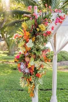 an outdoor ceremony setup with flowers and greenery on the altar, surrounded by palm trees