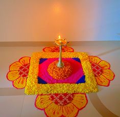 a decorated table with a lit candle on it and an intricately designed rug in the middle