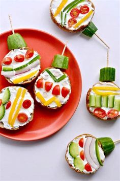 small appetizers with vegetables and cheese on them are arranged on a red plate