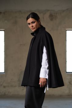 Introducing our Handmade Black Wool Cape - a true masterpiece of craftsmanship, designed to elevate your winter wardrobe to new heights. Meticulously crafted from 100% high-quality sheep wool, this cape is a testament to both warmth and style. With its unique poncho construction, this cape offers a contemporary twist on traditional winter outerwear. It features carefully designed openings for the arms, allowing for freedom of movement without compromising on coziness. The hidden button closure a Elegant Oversized Wool Poncho, Modern Cape For Workwear, Elegant Black Oversized Cape, Elegant Oversized Black Cape, Classic Winter Cape For Work, Elegant Fall Poncho For Work, Classic Winter Workwear Cape, Elegant Wool Poncho For Workwear, Elegant Fall Poncho For Workwear