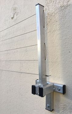 a metal pole mounted to the side of a building with two black brackets on it