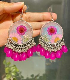 These handmade resin earrings feature a vibrant purple and pink original flower encased in a shimmering background, complemented by silver-tone metal and dangling beads. Perfect for adding a boho-chic touch to any outfit. Vibrant Purple, Earrings Simple, Resin Earrings, Pink Earrings, Simple Earrings, Jewelry Earrings Dangle, Boho Chic, Etsy Earrings, Dangle Drop Earrings