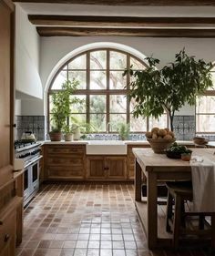 a kitchen with an arched window and tiled flooring is pictured in this image, there are potted plants on the counter