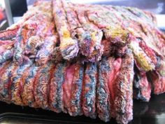 a pile of multicolored fabric sitting on top of a metal shelf in a store